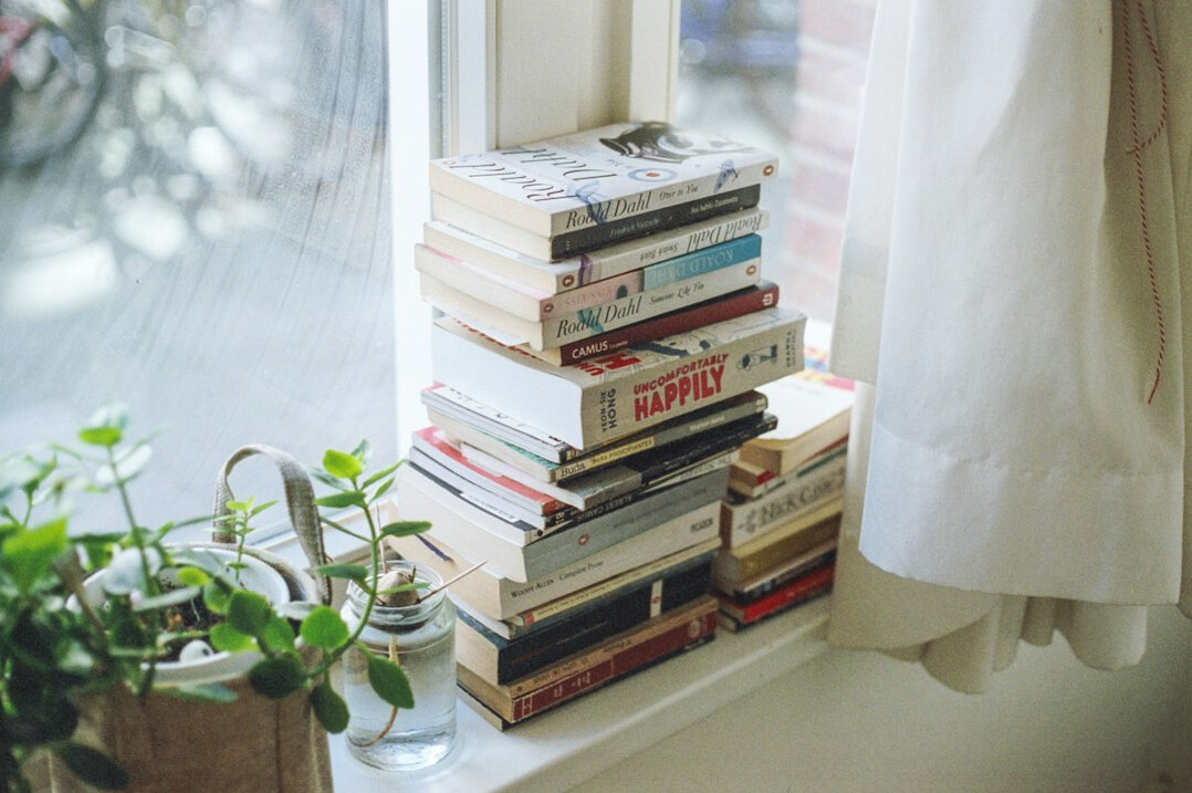 Stacked books next to a window